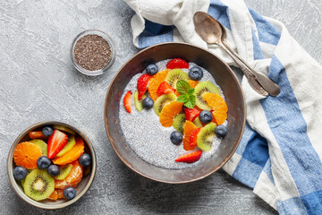 Chia puddind with fruit berry salad in bowl on grey background. Healthy breakfast. Top view