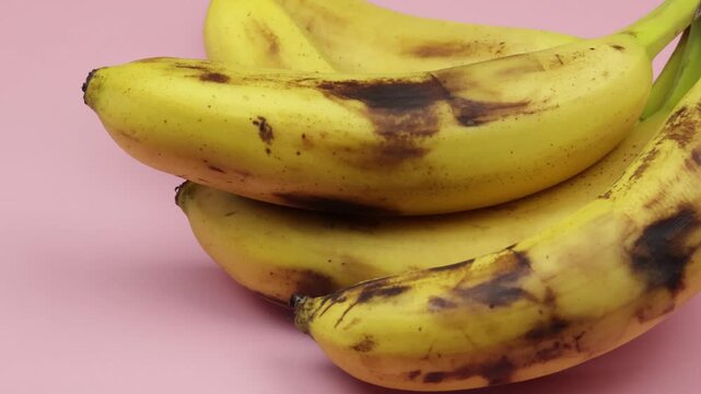 plusieurs bananes bien m&ucirc;res, en gros plan, sur un fond rose