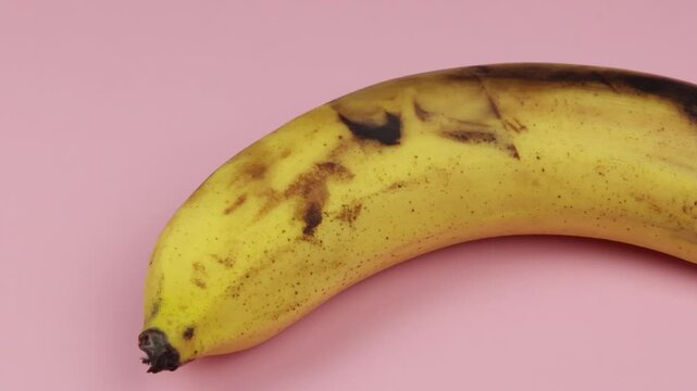 une banane, en gros plan, sur un fond rose