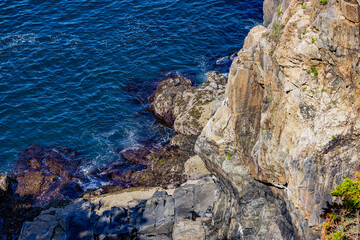 Gentle Atlantic Ocean touches the dramatic rocks on the coast of Maine
