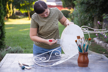 Painting an wrought iron chair outdoors, an eco-friendly re-use business.