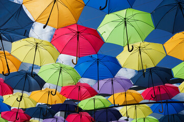 Colorful umbrellas against a blue sky. Tourist attraction with vibrant parasols creating a stunning visual display. Perfect for sightseeing and outdoor activities. Multicolored umbrellas hanging.