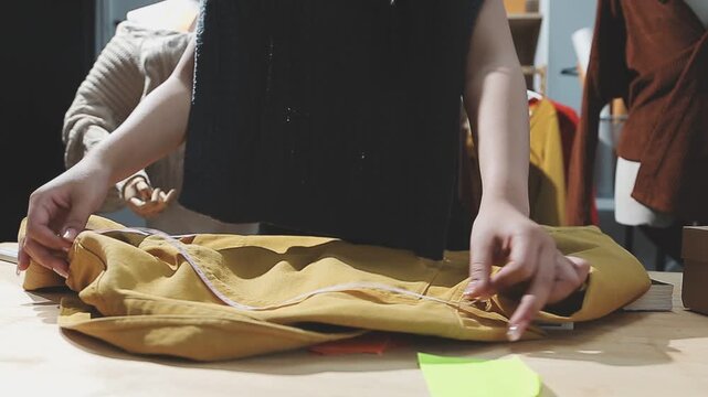 The designer is working and selecting colors for the clothing design in a good mood smiling with happiness at creating the work