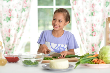 Cute happy girl coocking salad on kitchen
