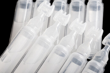 Eye drops background. Saline water capsules. Vials of saline background. Pharmacy product isolated on black. Small plastic medical bottle.