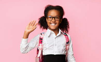 Hello, New School. African Schoolgirl Waving Hand Greeting Smiling To Camera On Yellow Background. Studio Shot
