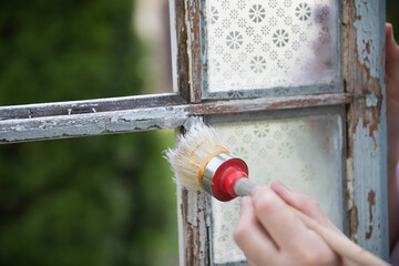 Painting a wooden vintage window outdoors, an eco-friendly re-use business.