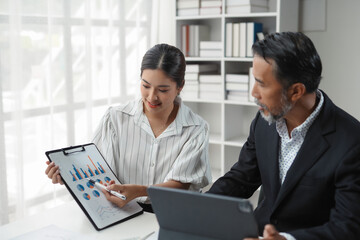 Business team collaborates while analyzing financial data using a digital tablet and charts on a clipboard