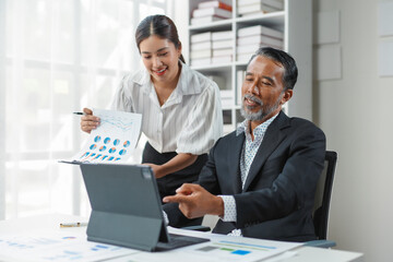 Business team is working together in the office, analyzing financial data on a digital tablet and paper documents