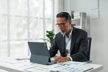 Senior executive is analyzing financial data on a tablet to create plans for business expansion