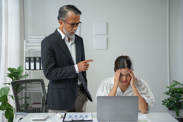 Senior manager reprimanding stressed employee with a headache in the office