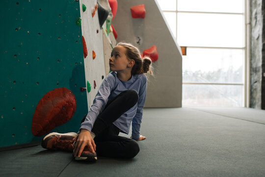 girl sat next to a climbing wall ready to boulder