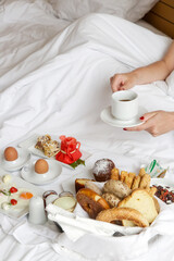 Young woman enjoying breakfast in the bed. Calm idyllic morning at home or hotel room