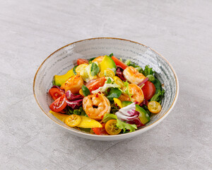 Salad with shrimps in sweet and sour sauce with mango and avocado. on a gray background