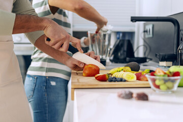 Beautiful young couple cooking together while cutting vegetables in the kitchen at home