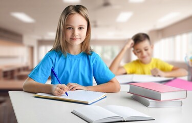 Smiling junior happy school student sittistng in classroom