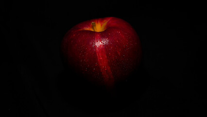 Roter Apfel mit Wassertropfen in stimmigem Licht