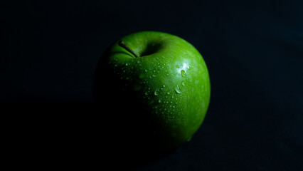 Grüner Apfel mit Wassertropfen in stimmigem Licht