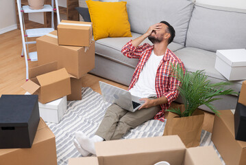 Tired male thinks about moving to new modern apartment choose reliable cargo transportation service putting remaining interior items in boxes made of thick cardboard