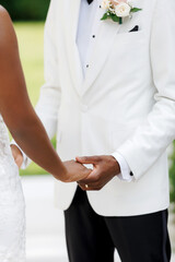 The groom holds the bride's hands at the wedding ceremony. Dark-skinned couple, bride and groom....