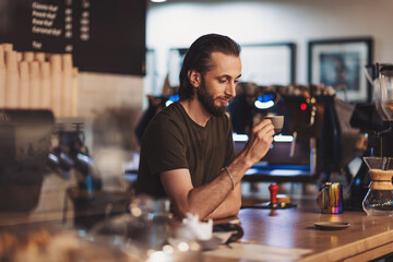 Pleasant barista drinking coffee. Happy male barista drinking coffee in cafe. cafe, free time and city concept. enjoying coffee break while relaxing. 