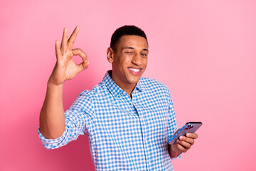 Photo of cheerful positive guy dressed checkered shirt showing okey winking eye chatting device...