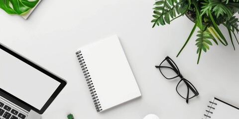 White blank notebook, glasses and computer on white background. A neatly organized modern workspace with a variety of office supplies, plants, and a laptop.