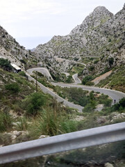 Top view of the serpentine road in the mountains. In the foreground is the curb of the road