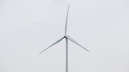 A sleek wind turbine against a cloudy sky, representing renewable energy and sustainable technology...