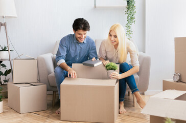 Happy man and woman putting things in moving boxes packing indoor. Preparing for renovation or leaving house. Copy space