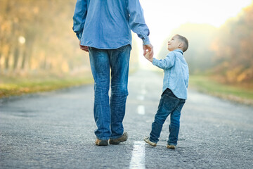 A Happy parent with child are walking along the road in the park on nature travel