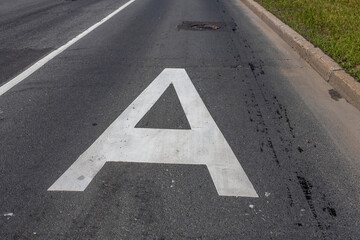 A white letter A is painted on a black road