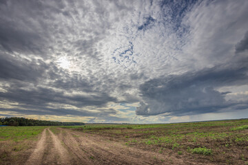 A cloudy sky with a sun in the background