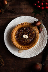 Individual serving pecan pie on a white plate with a dark brown wooden background for Thanksgiving and Christmas.