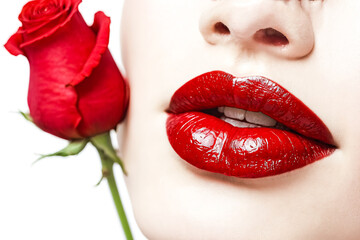 Closeup of a woman's lips with red lipstick and a red rose