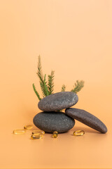 Yellow Soft Gel Capsule Omega 3, 6, 9 Fish Oil, Vitamin, Food Supplement Near Stone And Green Leaves. Natural Product Concept. Yellow Peach Background. Copy Space. Vertical. Selective Focus