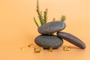 Yellow Soft Gel Capsule Omega 3, 6, 9 on Yellow Peach Background. Fish Oil, Vitamin, Food Supplement Near Stone And Green Leaves. Natural Product Concept. Copy Space. Horizontal Plane Selective Focus