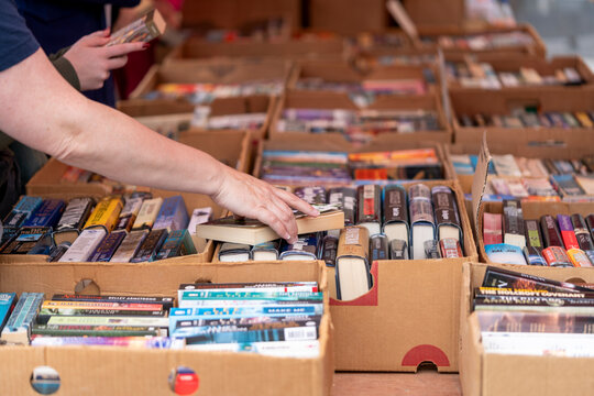 Dordrecht, Netherlands - July 7, 2024: Visitors explore second-hand books at the annual book market in Dordrecht, with 350 stalls throughout the city centre, a person reaching for a book.