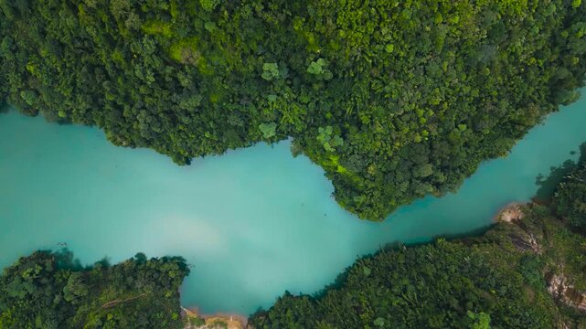Aerial view of lush green mountains and a serene river winding through the tropical forest along the Ha Giang Loop, Vietnam