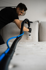 Dry cleaning of sofa pillows with extractor. Cleaner is washing off couch from stains, dust and...