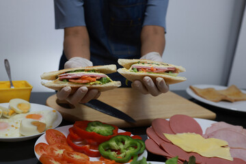 Women prepare ingredients and prepare breakfast sandwiches, fried eggs, and toast for the family