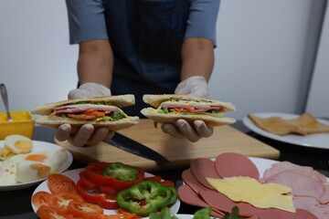Women prepare ingredients and prepare breakfast sandwiches, fried eggs, and toast for the family