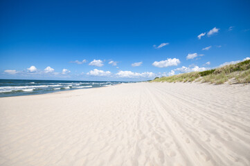 Empty, sandy beach and sea waves by sunny day