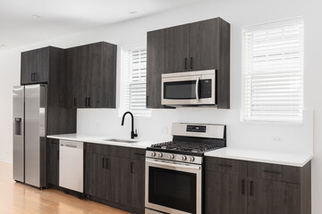 A modern bathroom with dark wood cabinets, white quartz countertops, stainless steel appliances,...