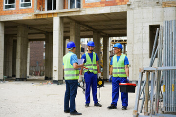 Engineer coworker in protective workwear discussing while working together at construction site