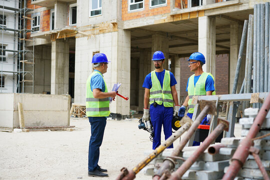 Engineer coworker in protective workwear discussing while working together at construction site