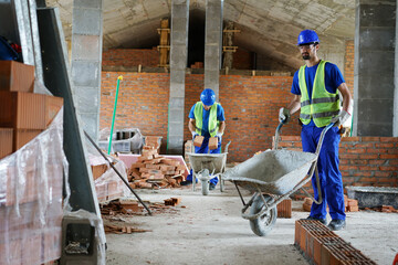 A construction worker pushes a construction cart for concrete or mortar
