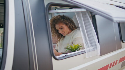 Pretty traveller sitting window campervan trailer looking smartphone close up.
