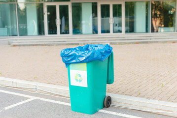 A green trash container designed to collect recyclable waste.