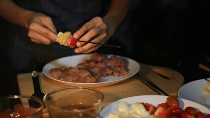 A woman prepares ingredients and prepares BBQ. Grilling for the party in the night. A woman is getting ingredients ready and grilling BBQ for a party at night.